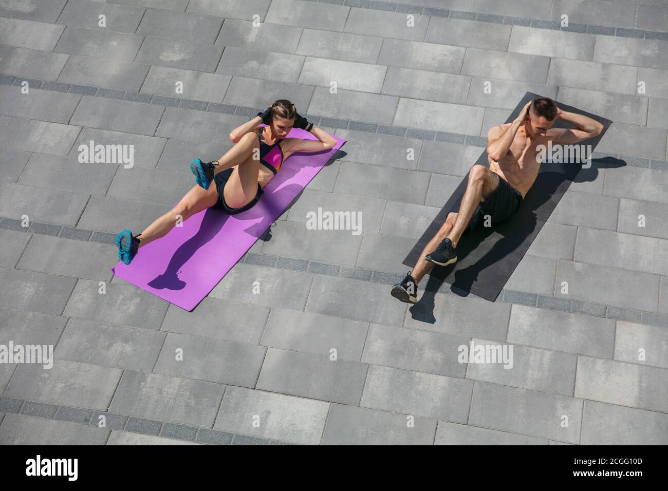 Junges Paar in Sport-Outfit tun Morgen-Workout im Freien. Mann und Frau tun Cardio-und Kraftübungen, üben Aktivität für den unteren und oberen Körper. Sport, gesundes Lifestyle-Konzept. Stockfoto