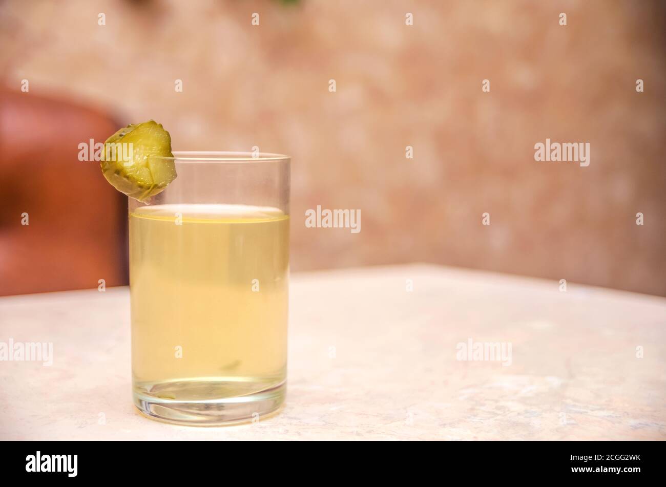 Ein Glas Gurke mit einem Stück Gurke auf dem Tisch. Traditionelle russische Kater Heilung Stockfoto