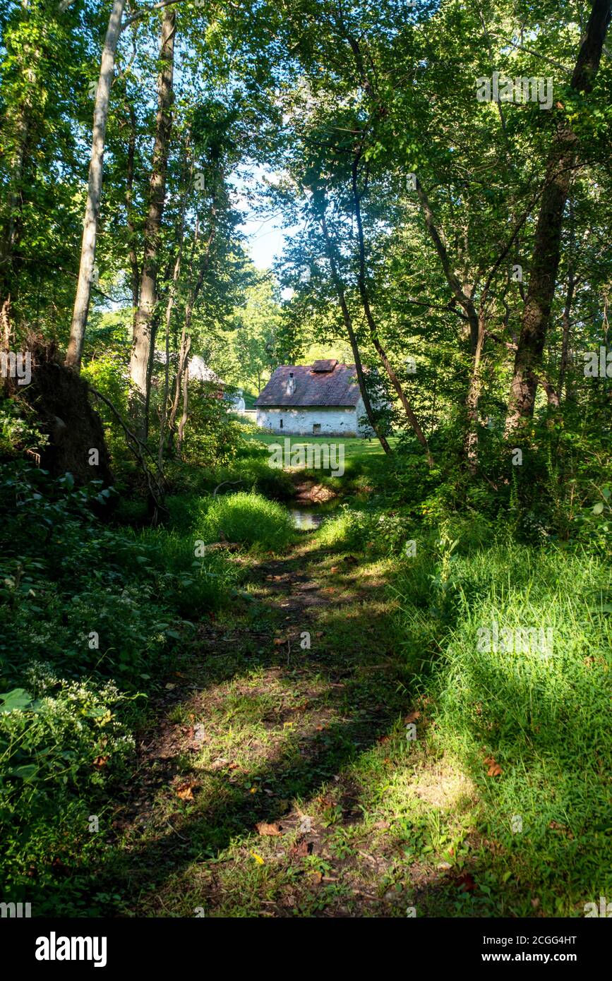 Malerische Szene einer weißen Steinhütte mit rotem Dach am Ende eines Waldwanderweges. Stockfoto