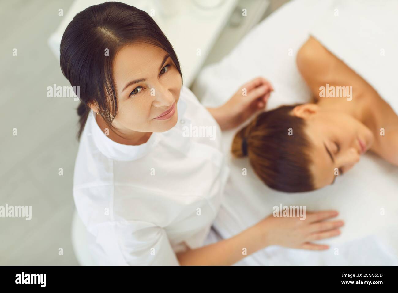 Frau Dermatologe sitzen und Blick auf die Kamera nach der Herstellung Gesichtsbehandlung Massage für junge Frau Stockfoto