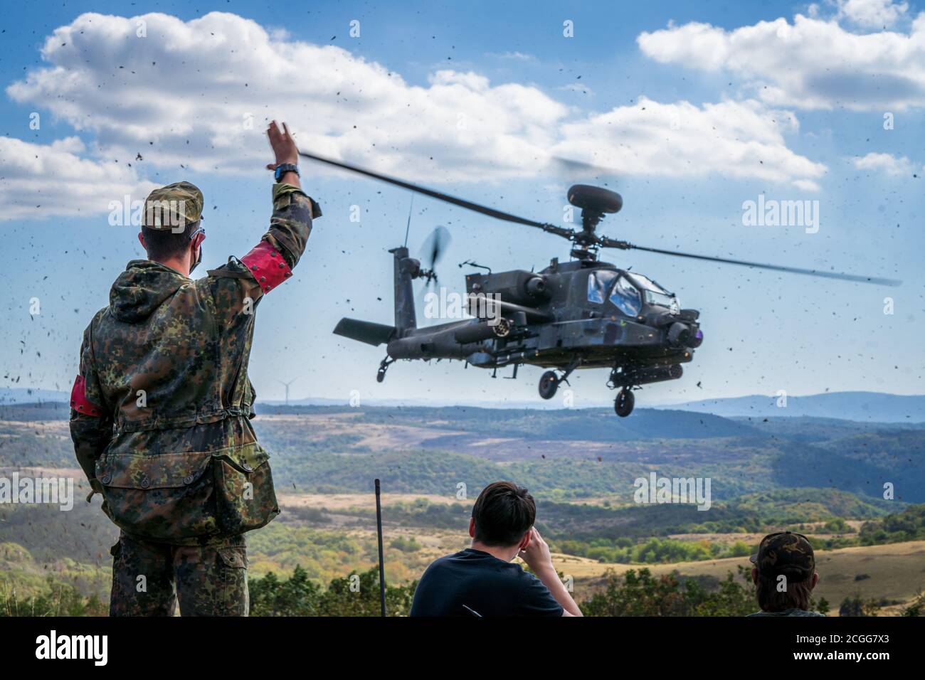 Ein Bundeswehrsoldat winkt zu einem AH-64 Apache Longbow von EINEM Co, 1-3 Attack Reconnaissance Bataillon auf Baumholder Trainingsgelände am 9. September. Ein Co, unterstützt von Elementen der D und E-Unternehmen zusammen mit Luftwaffe Mitarbeiter Wetteroffiziere, mit deutschen Joint Terminal Attack Controller von der Artillerie-Schule ausgebildet. Unterstützt wurde das Training auch von 155mm Haubitzen und 120mm Mörsern der Deutsch-Französischen Brigade. (USA Armee Foto von Maj. Robert Fellingham) Stockfoto