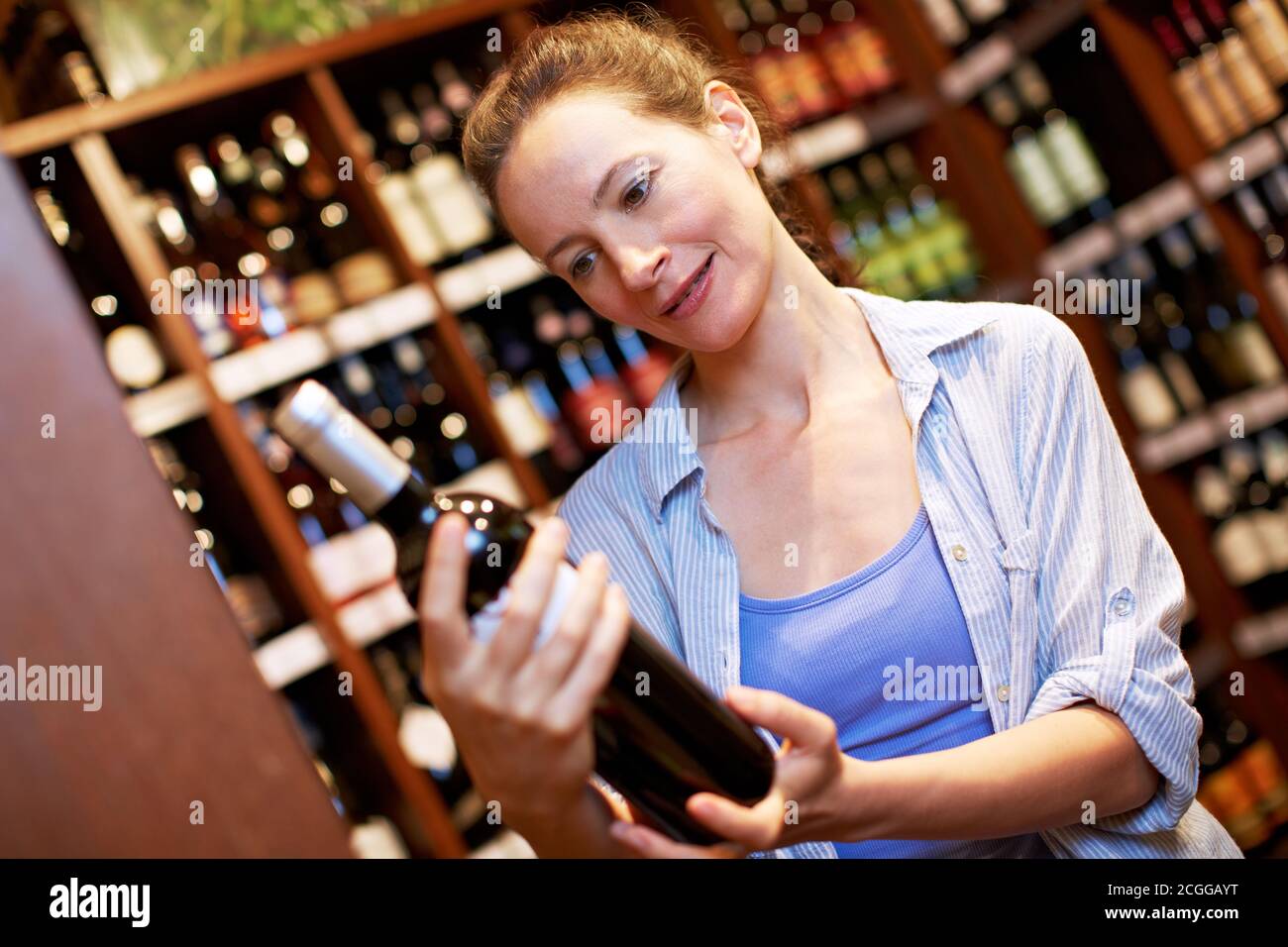 Ältere Frau kauft eine Flasche Rotwein in der Supermarkt Stockfoto