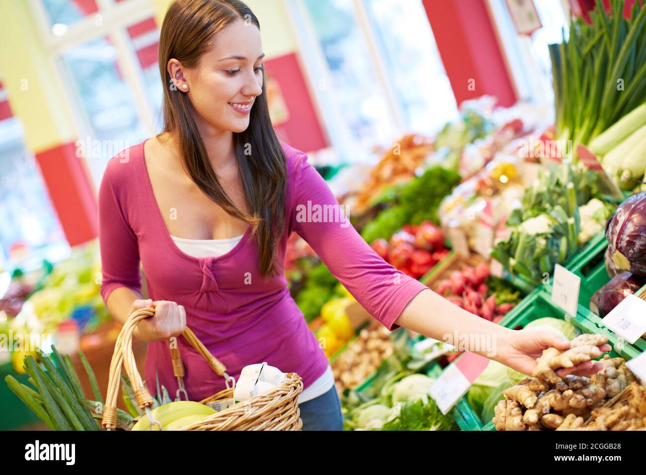 Junge lächelnde Frau kauft Gemüse im Reformhaus Stockfoto
