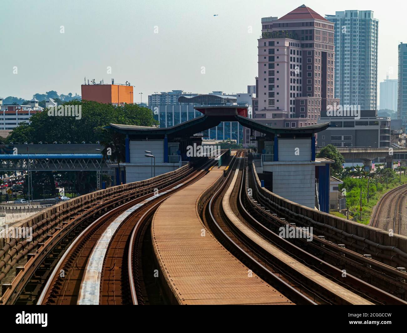 Mit dem Zug an einem sonnigen Tag zur Arbeit gehen Mit Stadtbild und Gebäude am Horizont Stockfoto