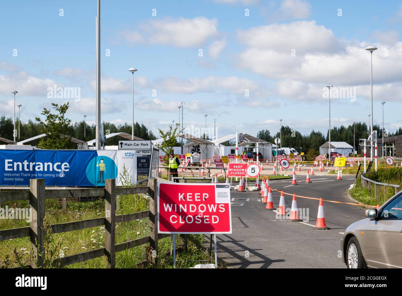 Auto geht in der Einfahrt mit Schildern zu Covid-19 fahren durch Testzentrum NHS Coronavirus Test und Trace Anlage. York, North Yorkshire, England, Großbritannien Stockfoto