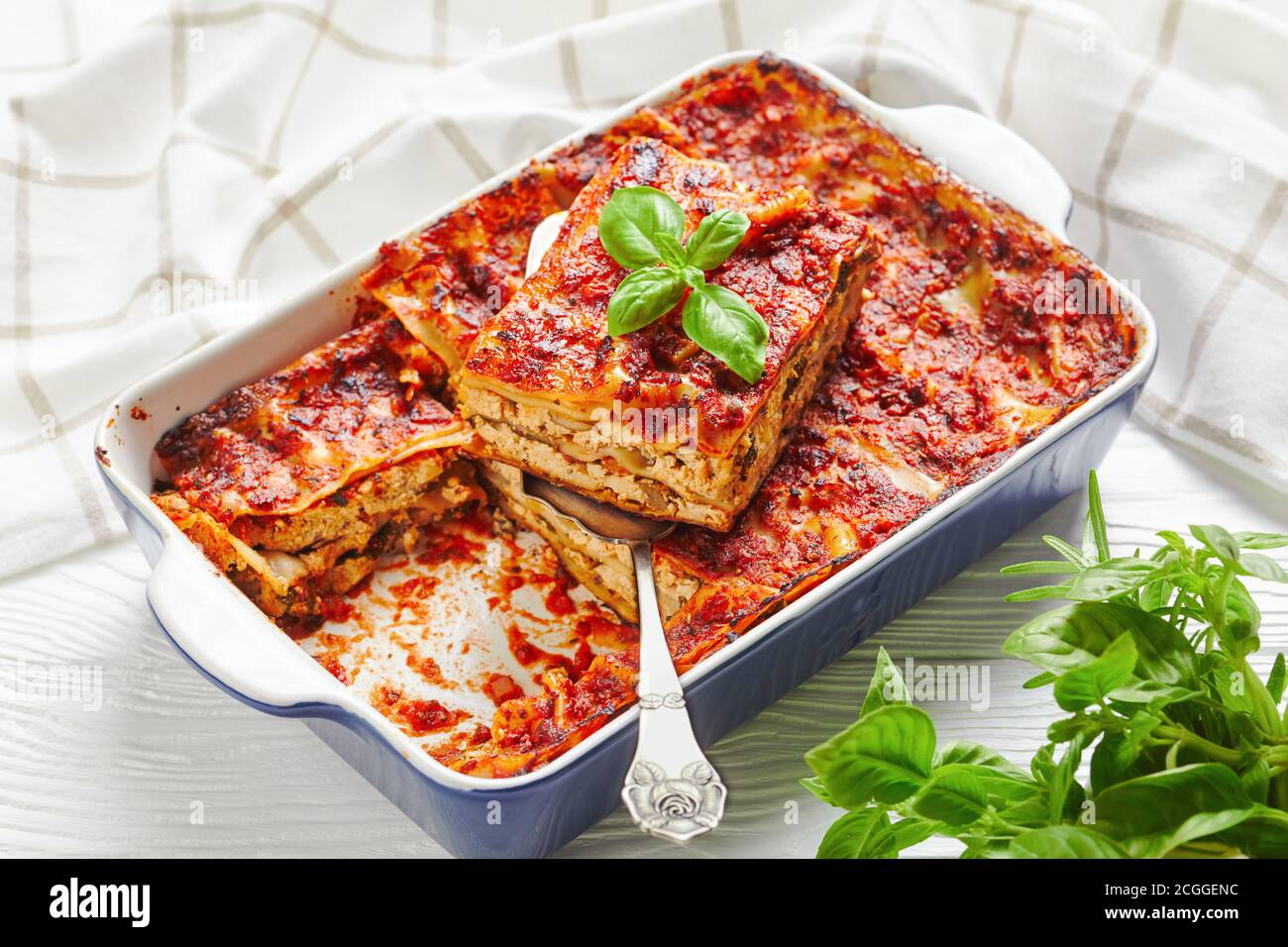 Fleischlose fettarme Lasagne mit festem Tofu, Pilzen, Tomatensauce, italienische Würze, im Ofen gebacken, serviert auf einer Backform mit frischen Kräutern auf einem Stockfoto