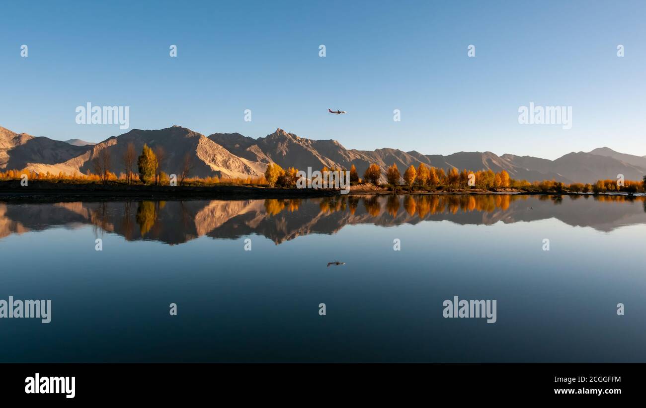 Bei Sonnenaufgang fliegt ein Flugzeug über Berge und Flüsse. Stockfoto