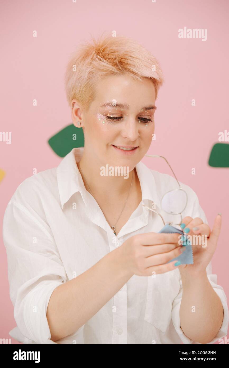 Lächelnde junge Frau mit kurz gefärbten blonden Haaren Sterne Auge Make-up-Reinigungsgläser Stockfoto