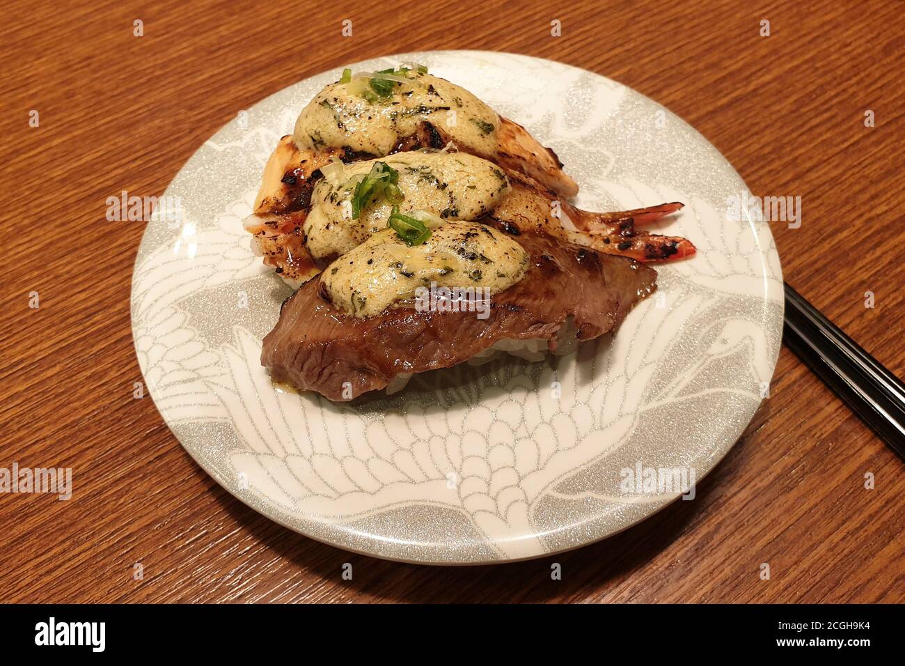 Knoblauchkäse-Sushi mit gegrilltem Rindfleisch, Fisch und Garnelen gekrönt. Beliebtes Sushi-Restaurant mit Förderband in Seoul. Stockfoto