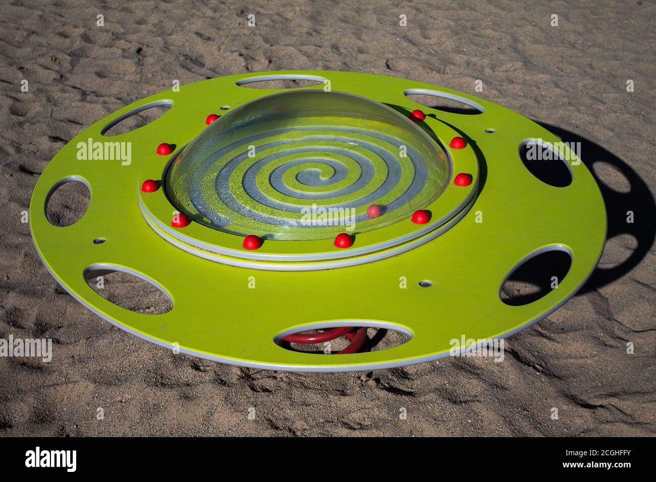 Spielen Gerät UFO Wippe. Ein gelber Teller mit Acrylabdeckung, der mit roten Halbkugeln befestigt ist. Stockfoto