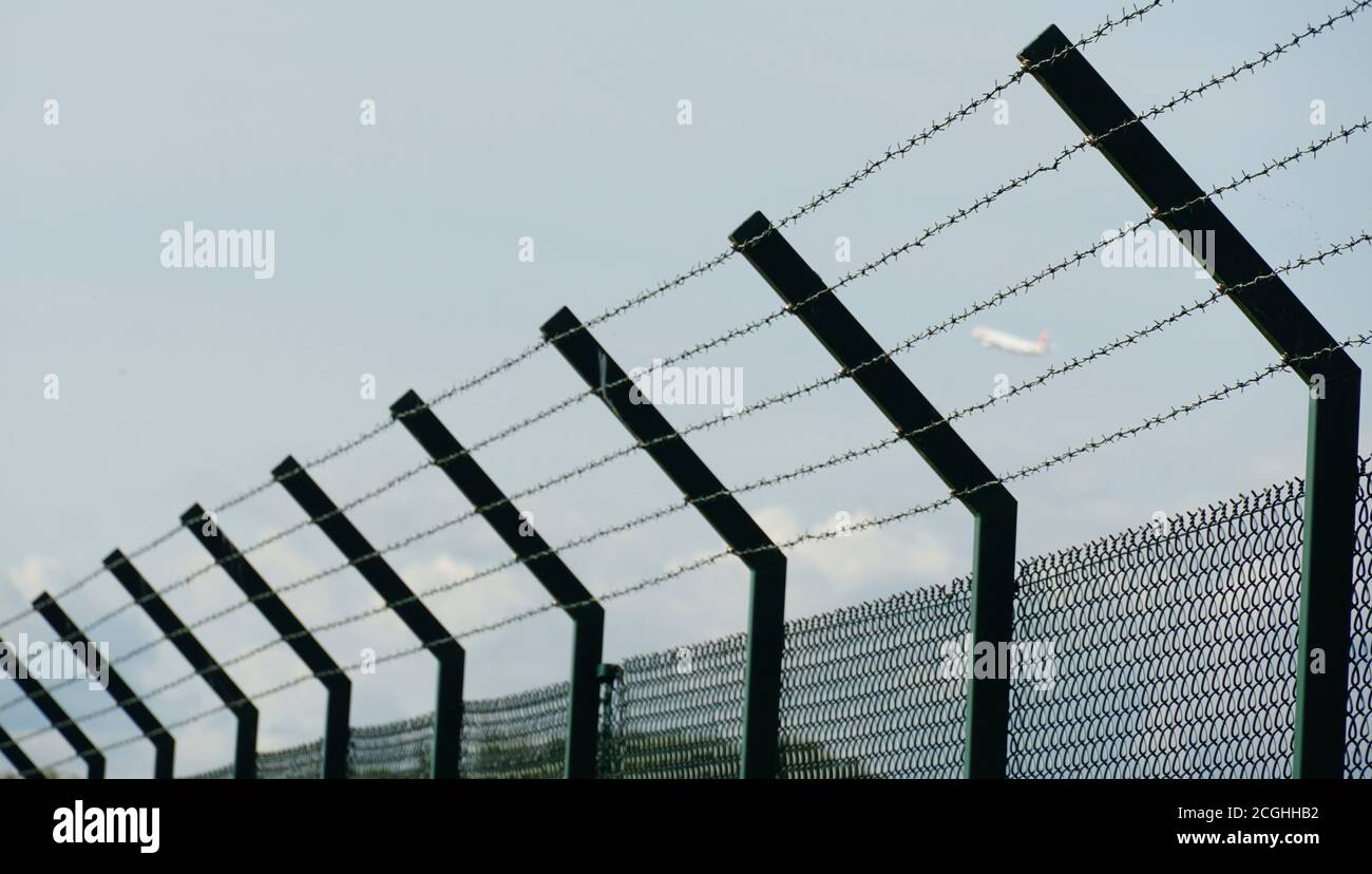 Ein hoher Zaun um das Gelände des Flughafens Zürich aus geflochtenem Draht und mit Stacheldraht als Schutz vor unbefugtem Betreten versehen. Stockfoto