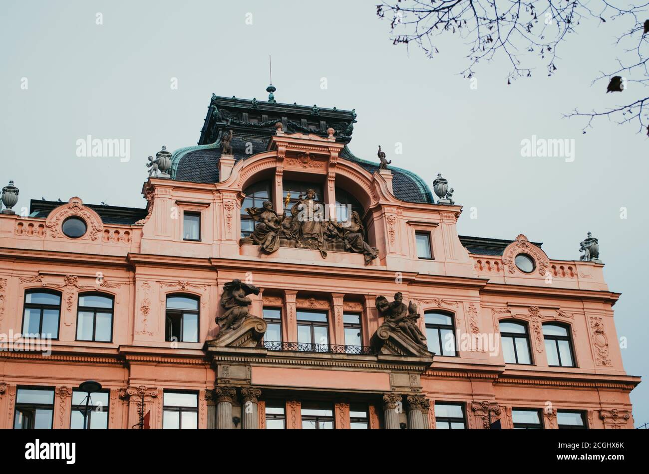 Prague, Czechia - EIN schrulliges, pinkfarbenes Gebäude in der Nähe des Nationalmuseums und mit Engelsstatuen im Eingang. Stockfoto