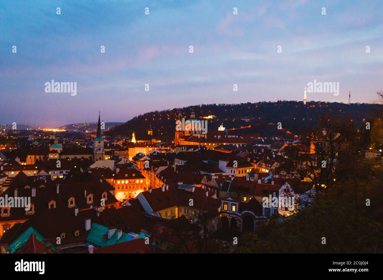 Prag, Tschechien - EIN magischer Blick auf die beleuchteten Straßen der Hauptstadt und ihre braunen Dächer während der Dämmerung. Stockfoto