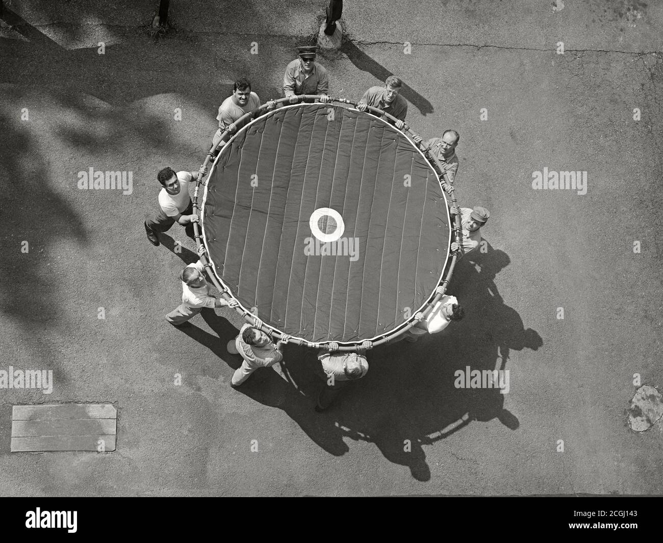 Ein Rettungsteam hält ein „Rettungsnetz“, das verwendet wird, um Opfer zu fangen, die aus einem Hochhausbrand springen, um 1950. Stockfoto