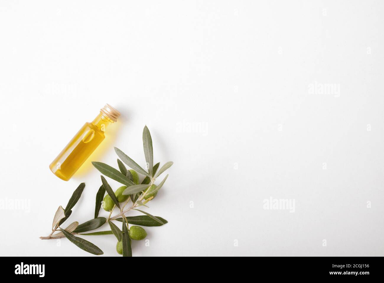 Glas und Olivenzweig voller Oliven auf weißem Tisch. Draufsicht. Stockfoto