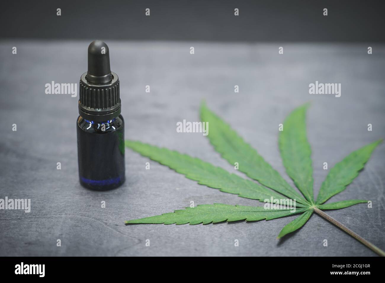 Glasflasche mit CBD-Öl und Hanfblättern auf schwarzem Holzhintergrund. Organische und natürliche Kosmetik- und Kosmetikprodukte auf Hanfbasis. Medizinisches Cannabis. Stockfoto