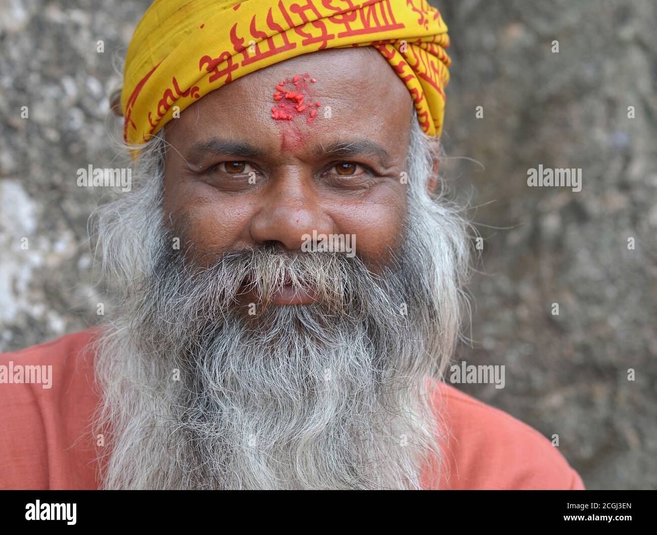 Der alte nepalesische Bettler und Hindu-Anhänger mit roter Reiskleie auf der Stirn lächelt für die Kamera. Stockfoto
