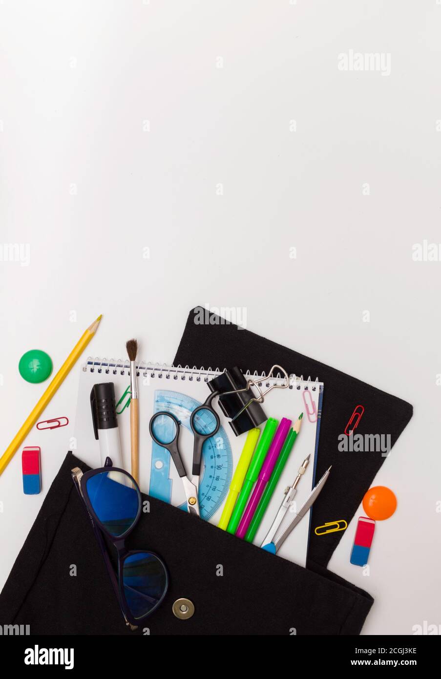 Schulabschluss. Bürobedarf in einem offenen schwarzen Rucksack. Weißer Hintergrund, freier Platz für Text. Stockfoto