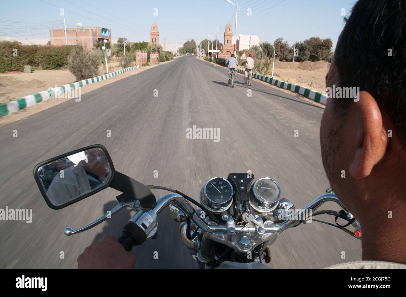 Ein arabischer ägyptischer Mann, der mit seinem Motorrad durch das Dorf Al Qasr in der Oase Dakhla in der westlichen Wüstenregion, im New Valley, Ägypten, fährt. Stockfoto