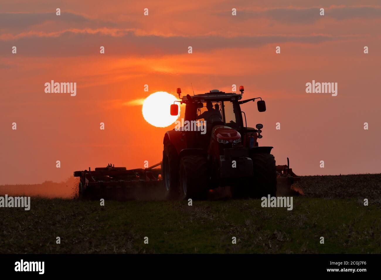 Massey Ferguson 7725 Traktor, erschütternd ein Ackerfeld, bei Sonnenuntergang. Stockfoto