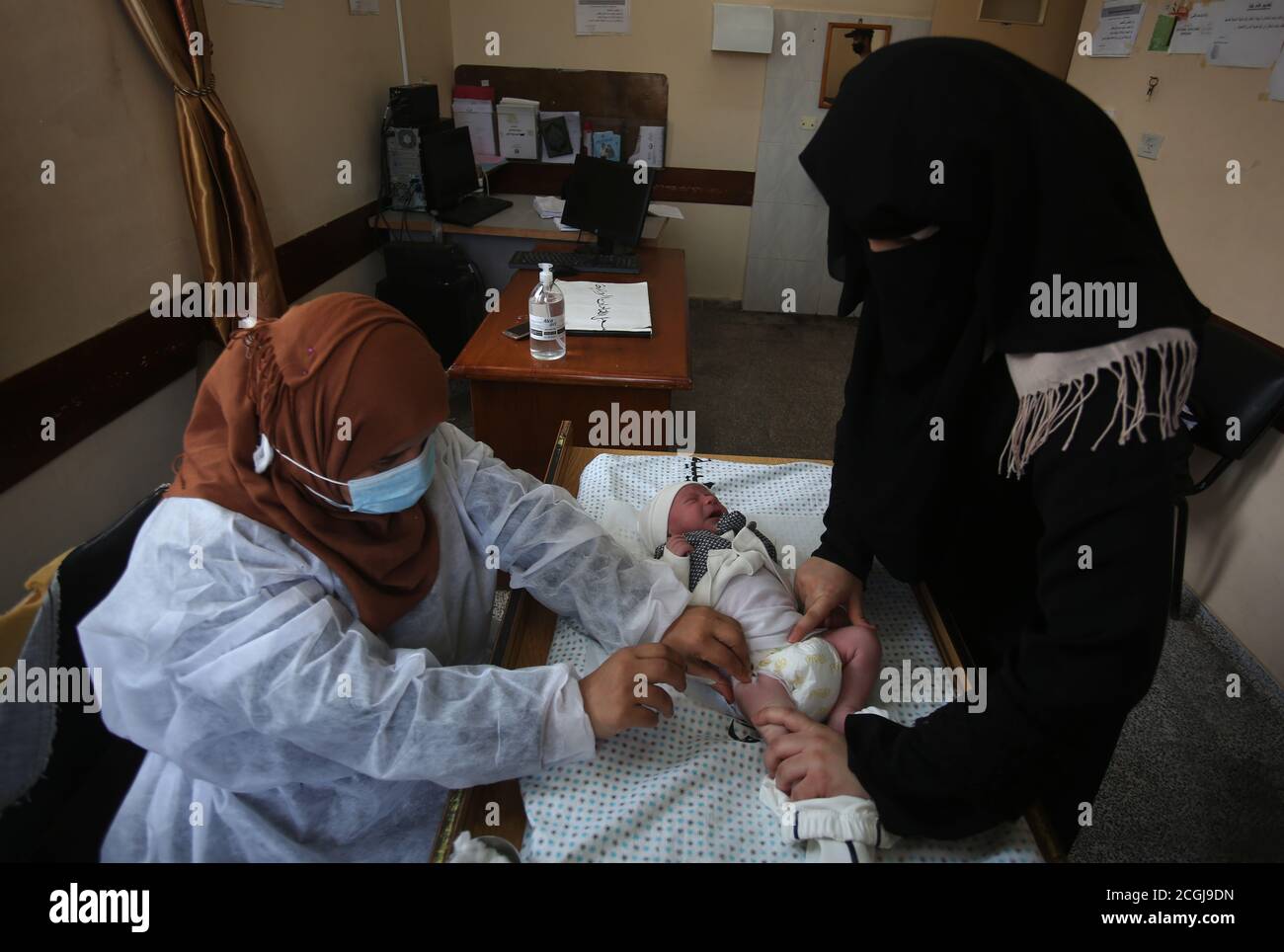 Gaza, Palästina. September 2020. Ein in Schutzkleidung gekleideter Arzt, der während der Coronavirus-Krise (COVID-19) einem Neugeborenen den Impfstoff gegen das menschliche Immunsystem in einem Gesundheitszentrum verabreicht. Kredit: SOPA Images Limited/Alamy Live Nachrichten Stockfoto