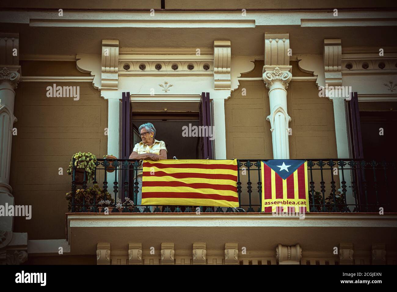 Barcelona, Spanien. September 2020. Eine Frau schaut während des 'Diada' (katalanischer Nationalfeiertag) in Barcelona vom Balkon aus auf den ANC-Hauptakt. Aufgrund der Corona-Krise ist die Teilnahme an der Diada in diesem Jahr viel geringer, um die Ausbreitung des Virus zu verhindern. Quelle: Matthias Oesterle/Alamy Live News Stockfoto