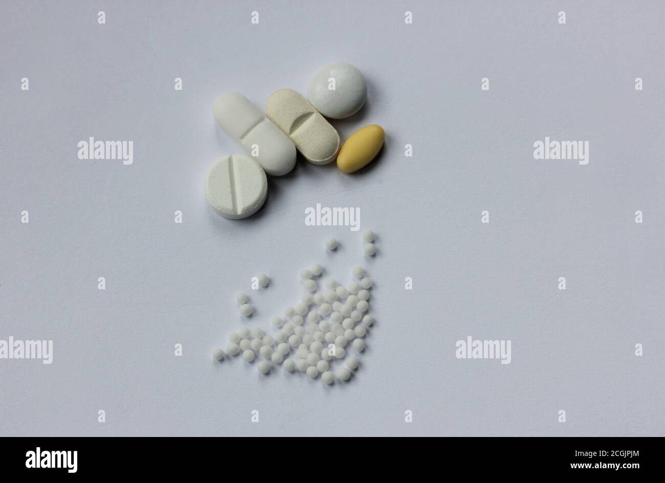 Homöopathische Kügelchen neben den Pillen der konventionellen Medizin. Stockfoto