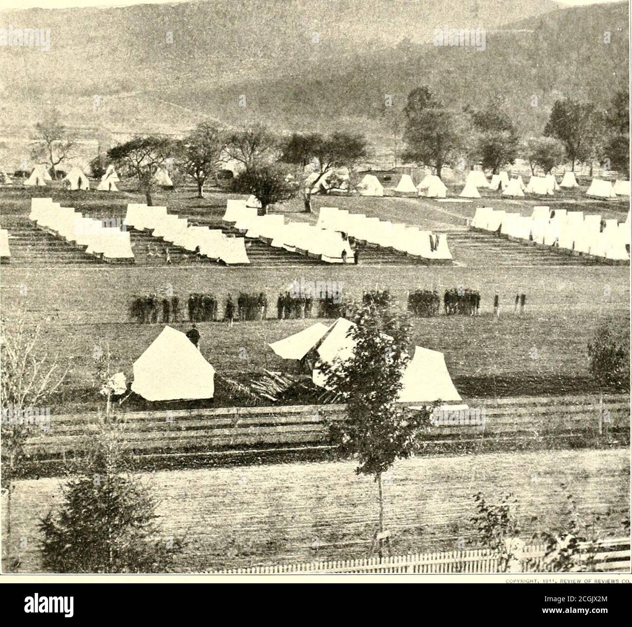 . Die fotografische Geschichte des Bürgerkrieges: In zehn Bänden. ÜBERPRÜFUNG VON RENEWS HI. WACHWECHSEL IM GEFÄNGNIS VON ELMIRA, 1864 Dieses Foto von den Vierteln der Wachen, die die Tausenden von konföderierten Gefängnisinhaftierten in Elmira bewachten, zeigt, dass die Bedingungen außerhalb des Lagers viel besser waren als in. Die langen Schatten der regelmäßigen Zelten deuten deutlich darauf hin, dass es am späten Nachmittag genommen wurde. Das Blatt auf den Bäumen fixiert die Jahreszeit als Sommer. Die Männer sind offenbar in Wachwechsel engagiert. Dr. E. F. Sanger, der an Elmira befestigte Chirurg, hatte große Schwierigkeiten, h zu bekommen Stockfoto