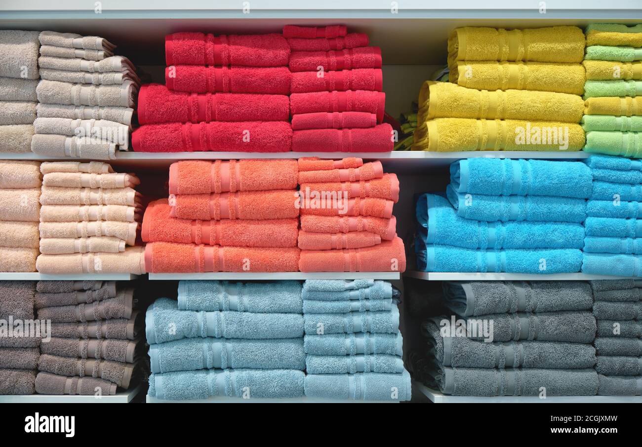 Stapel von bunten flauschigen Badetüchern auf Regal im Geschäft, Vorderansicht mehrfarbigen Textil-Hintergrund Stockfoto