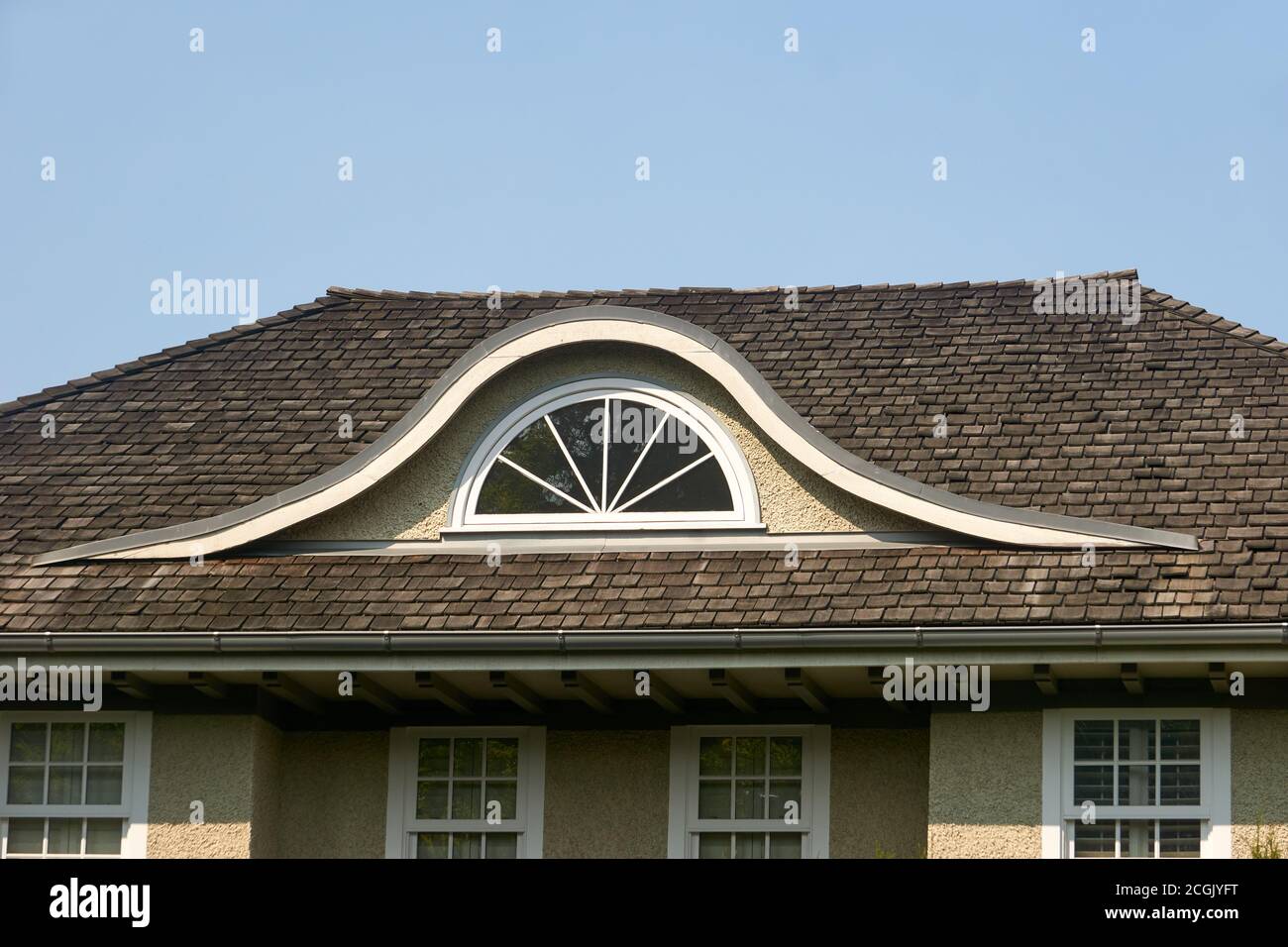 Halbkreisförmige gewölbte Dachfenster oder Augenbrauen Dormer in einer Zeder Schütteln Dach eines Hauses Stockfoto