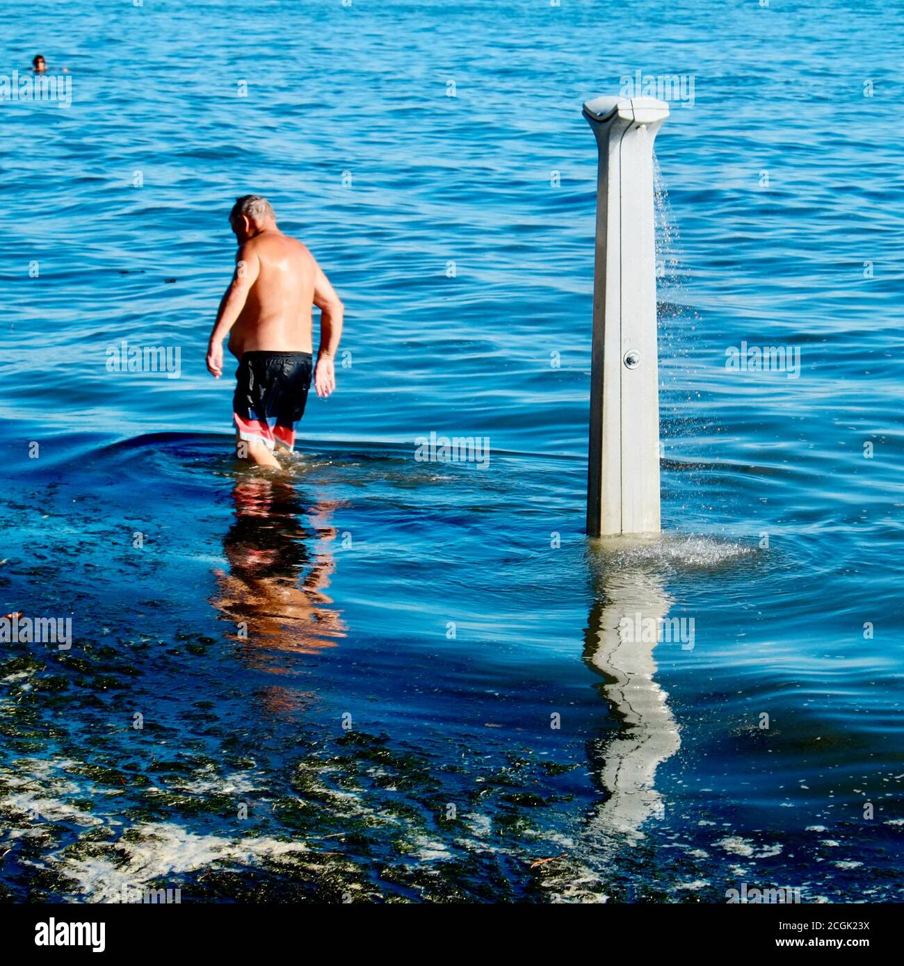 Mann, der an einem überfluteten Strand eine nutzlose Dusche nahm Stockfoto