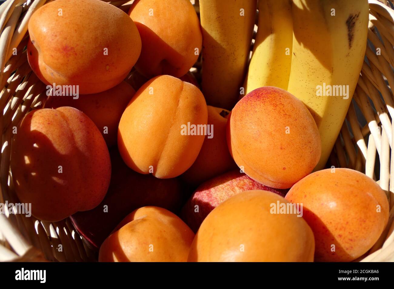 Früchte in einem hölzernen Obstkorb - Nahaufnahme gesunde frische Bananen, Aprikosen und Äpfel Stockfoto
