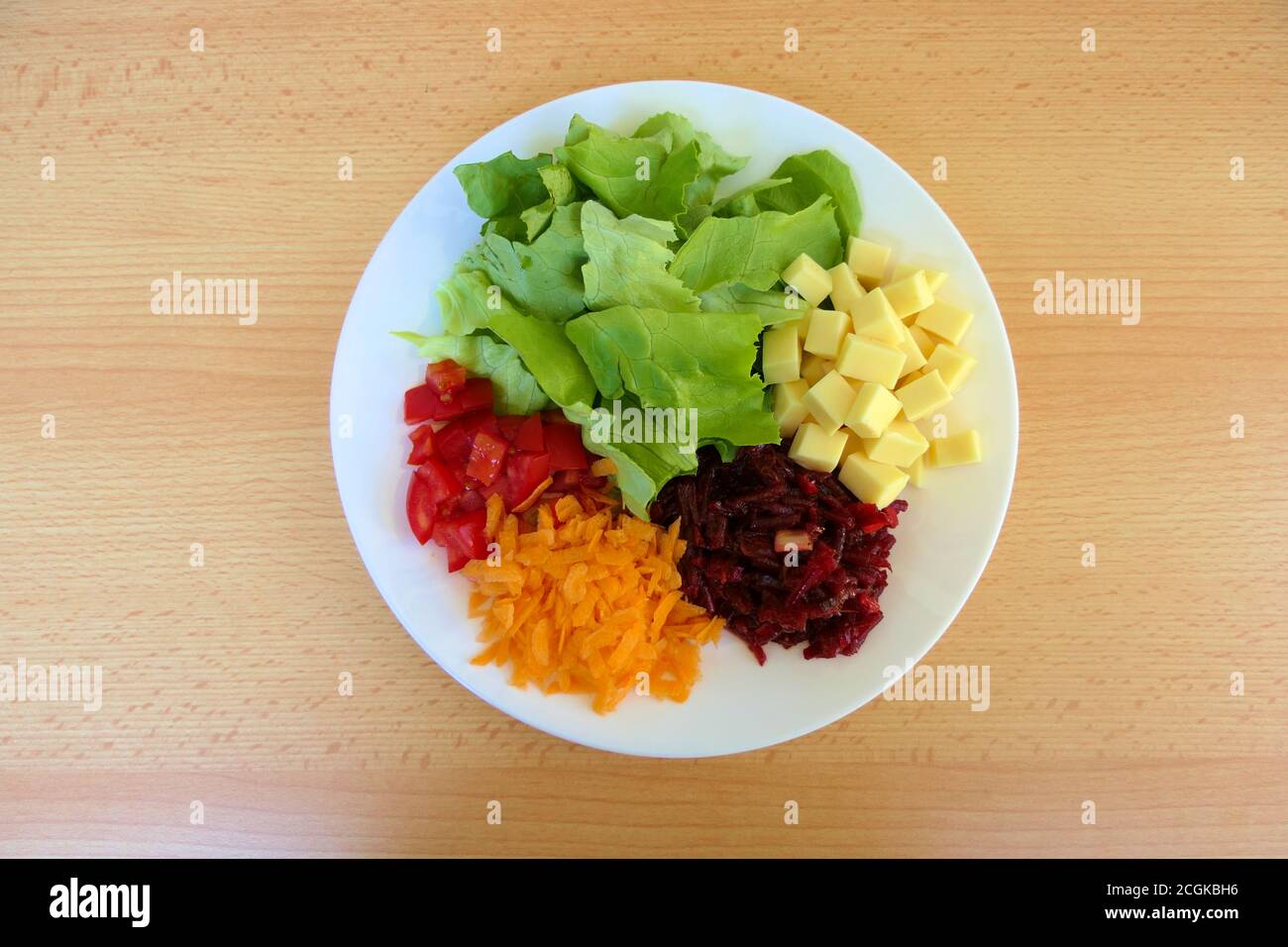 Draufsicht auf einen gesunden, selbstgemachten vegetarischen proteinreichen Salatteller mit grünem Salat, geriebenen Karotten und Rote Beete sowie gehackten Tomaten und Käse Stockfoto