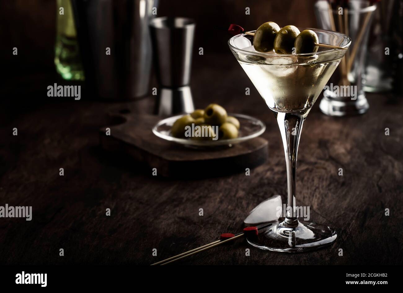 Martini-Cocktail, mit trockenem Wermut, Wodka und grünen Oliven, Bar-Theke aus Vintage-Holz mit Bar-Werkzeugen Stockfoto