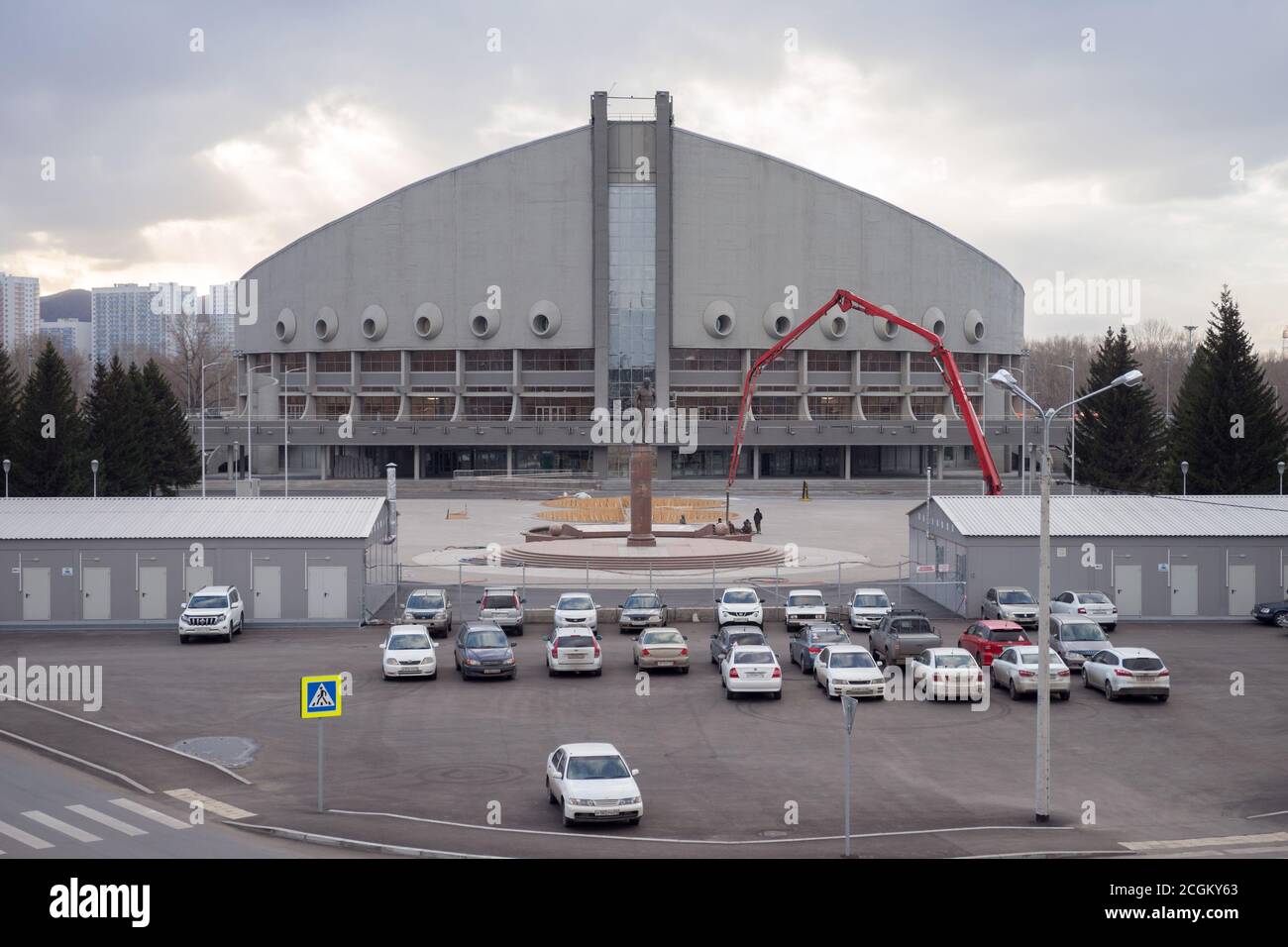 Autos vor dem Ivan Yarygin Sports Palace, Winter Universiade 2019 Veranstaltungsort, auf der Insel der Ruhe in Krasnoyarsk Stadt geparkt. Stockfoto