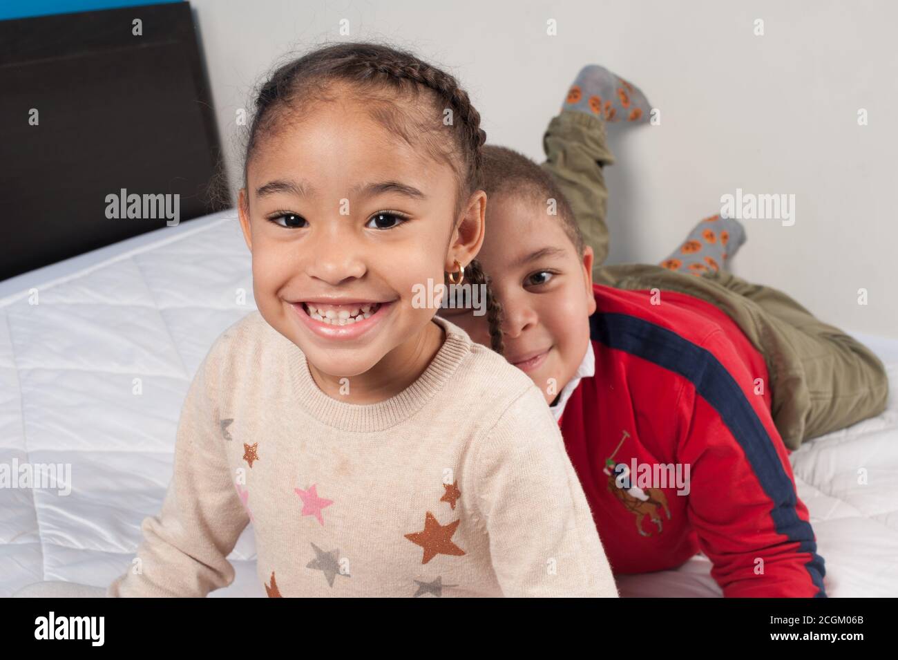 4 Jahre altes Mädchen mit 6 Jahre alten Jungen, beide posieren für die Kamera, lächelnd, Freunde Stockfoto