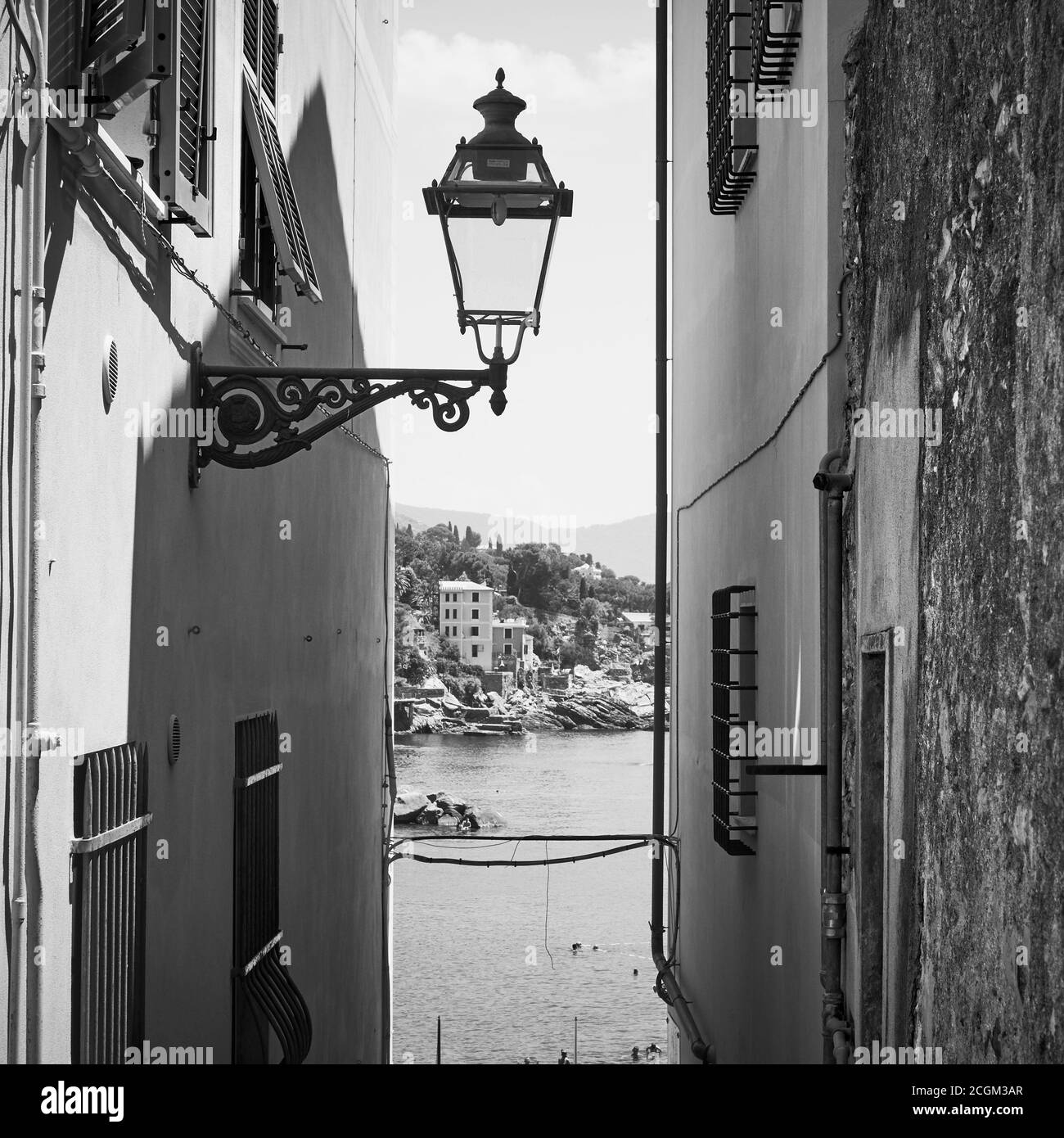 Alte Gasse mit Vintage-Straßenbeleuchtung, die zum Meer in Bogliasco Stadt in der Nähe von Genua, Italien führt. Schwarz-Weiß-Fotografie, italienische Landschaft Stockfoto