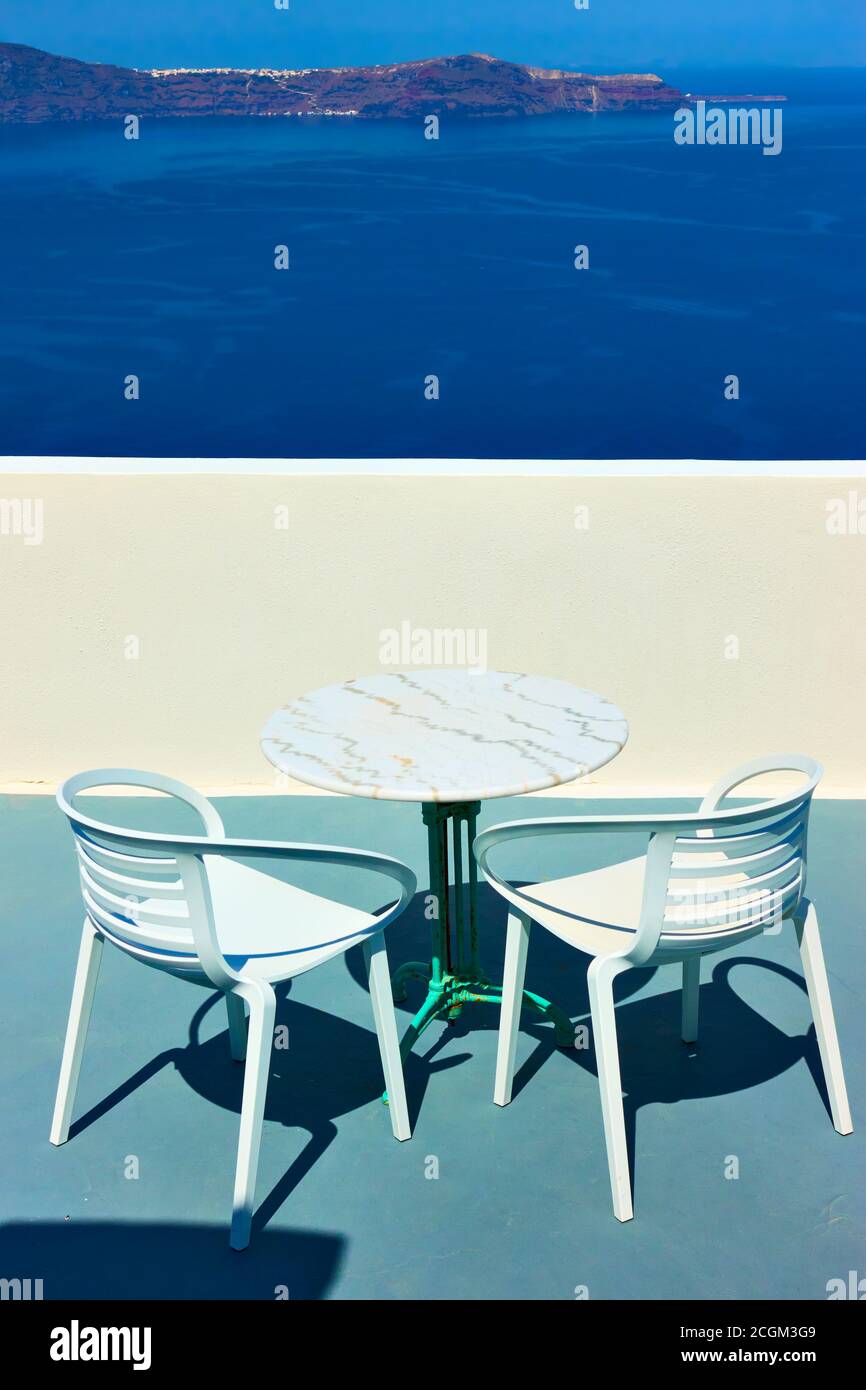 Terrasse über dem Meer mit Tisch und zwei Sesseln auf Santorini, Griechenland. Blick auf ein griechisches Resort Stockfoto