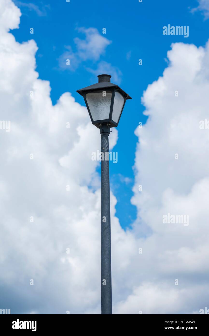 Vertikale Aufnahme eines Laternenpfostens gegen einen blau bewölkten Himmel. Stockfoto