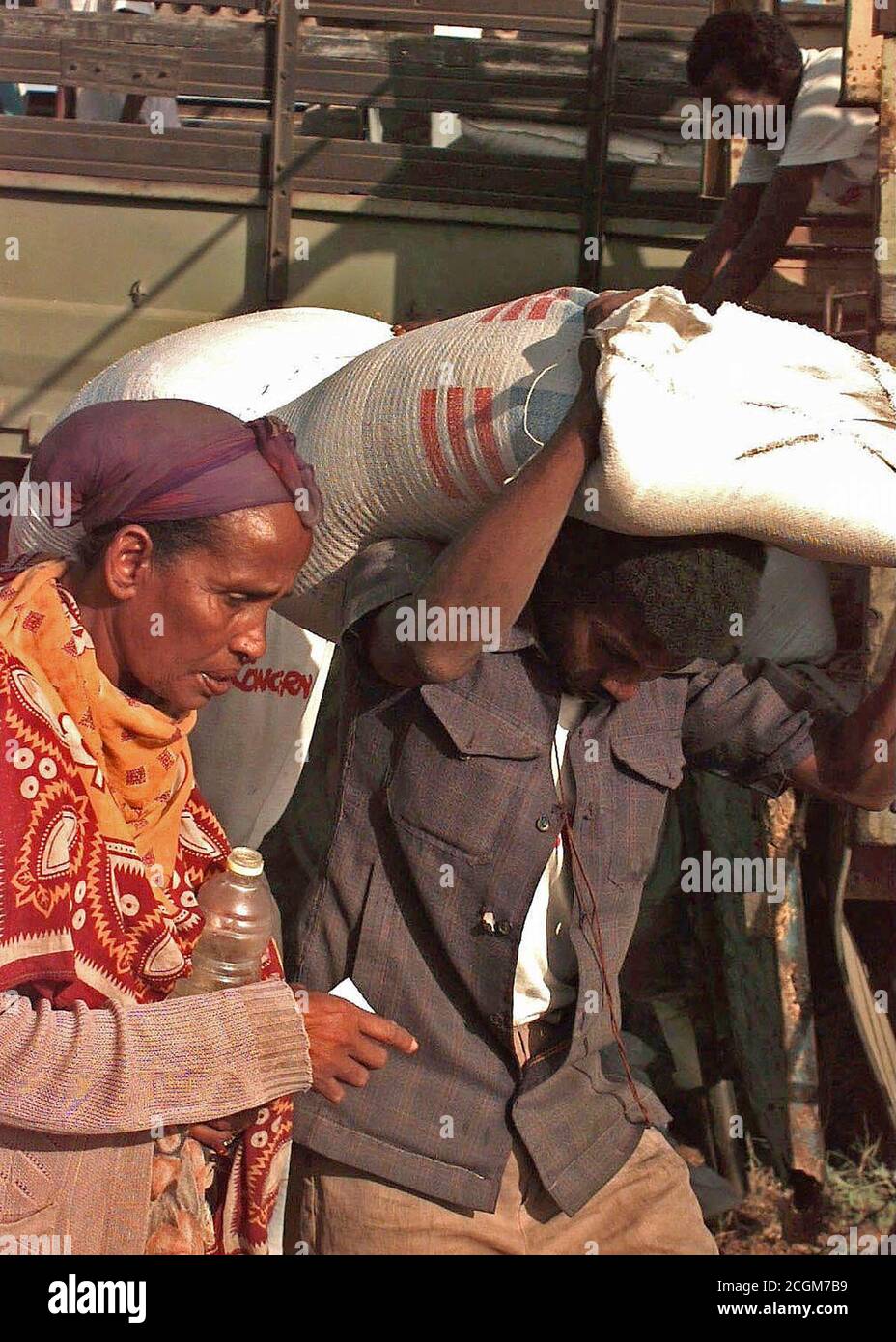 1993 - Gerade auf Schuß eines somalischen Mann, der einen 50 kg Sack Mais über seinen Kopf. Er trägt es für eine somalische Frau, die in den Frame links ist. Das Essen wird von der irischen Hilfsorganisation Sorge verteilt. Die Lebensmittel und Vorräte sind in der direkten Unterstützung der Operation Restore Hope. Stockfoto