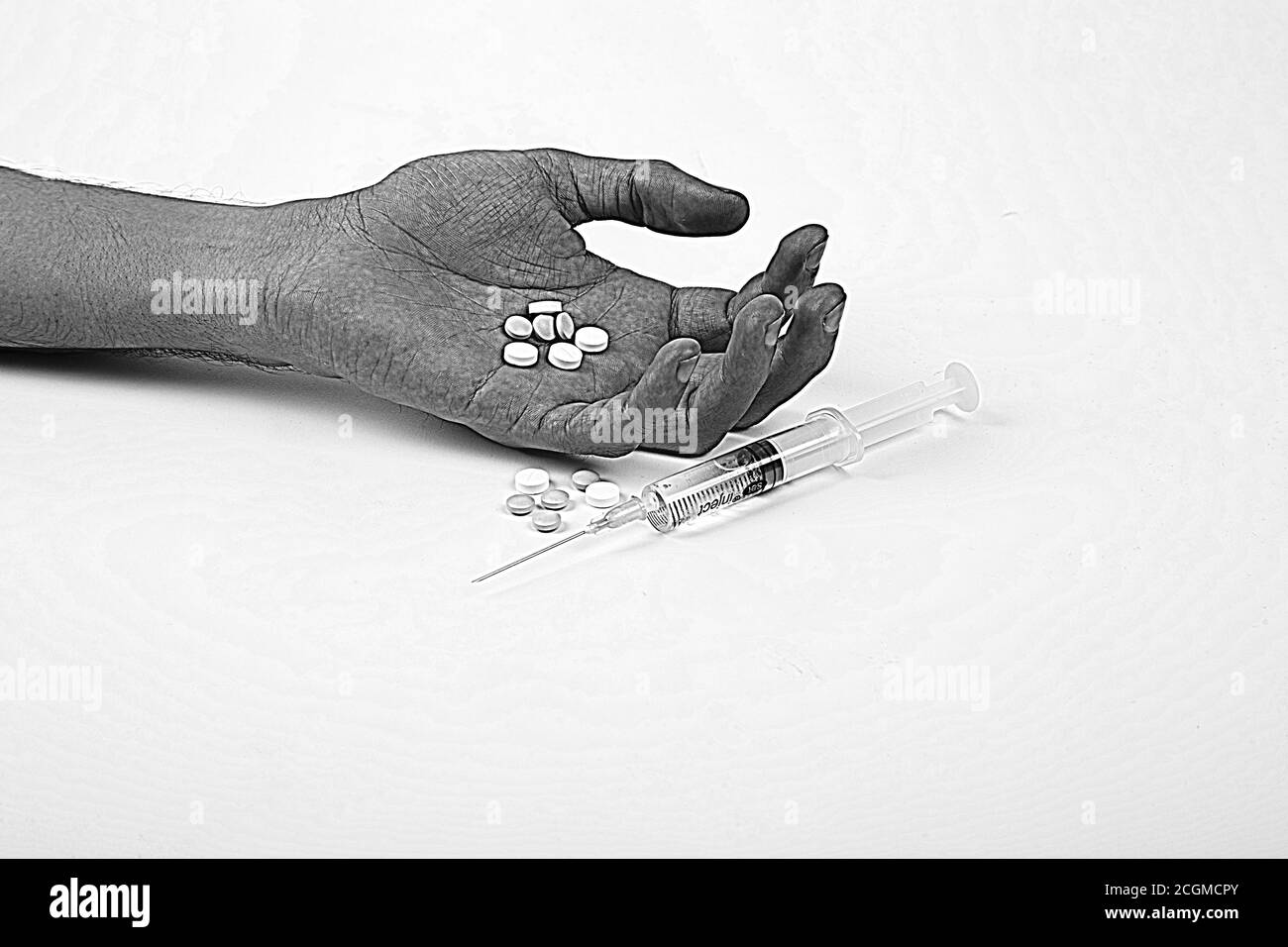 Drogenabhängigkeit Konzept - passive Hand mit Mantel, Pillen und Injektion, auf weißem und isoliertem Hintergrund, Balck und weißes Foto Stockfoto