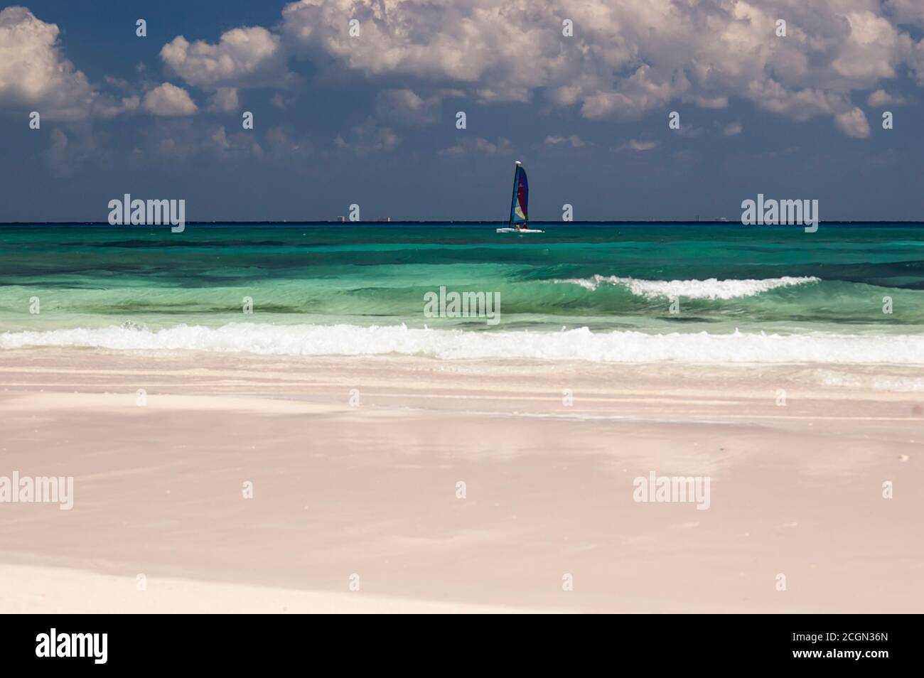 Ein Tourist segelt vor einem karibischen Strand in den Tropen. Im Hintergrund der blaue Himmel und weiße Wolken. Mexikanische Karibik Stockfoto