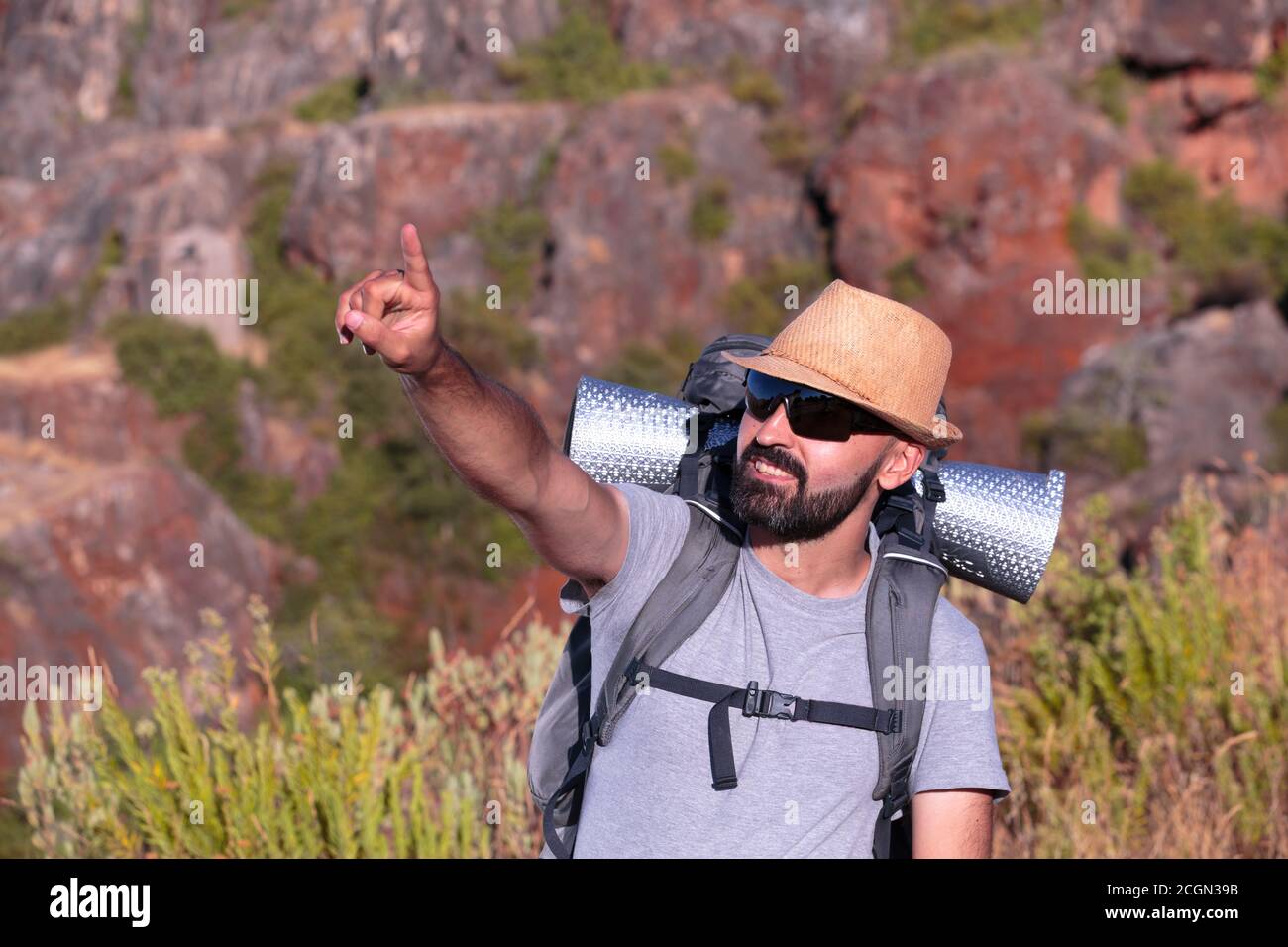 Hispanischer männlicher Trekker mit Sonnenbrille, die lächelt und zeigt Der Rahmen Stockfoto