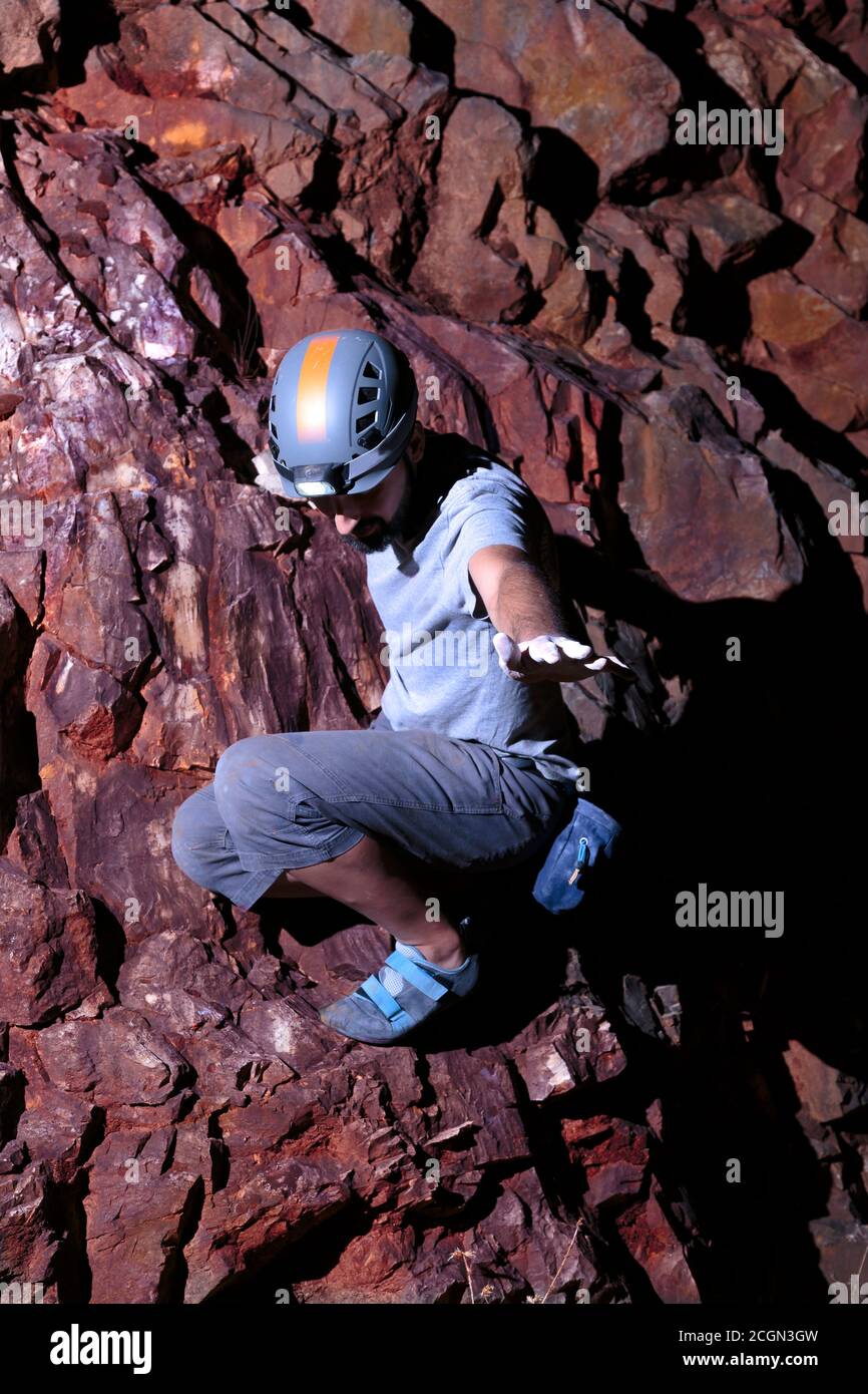 Selbstbewusster hispanischer Bergsteiger winkt und schaut nach unten Stockfoto