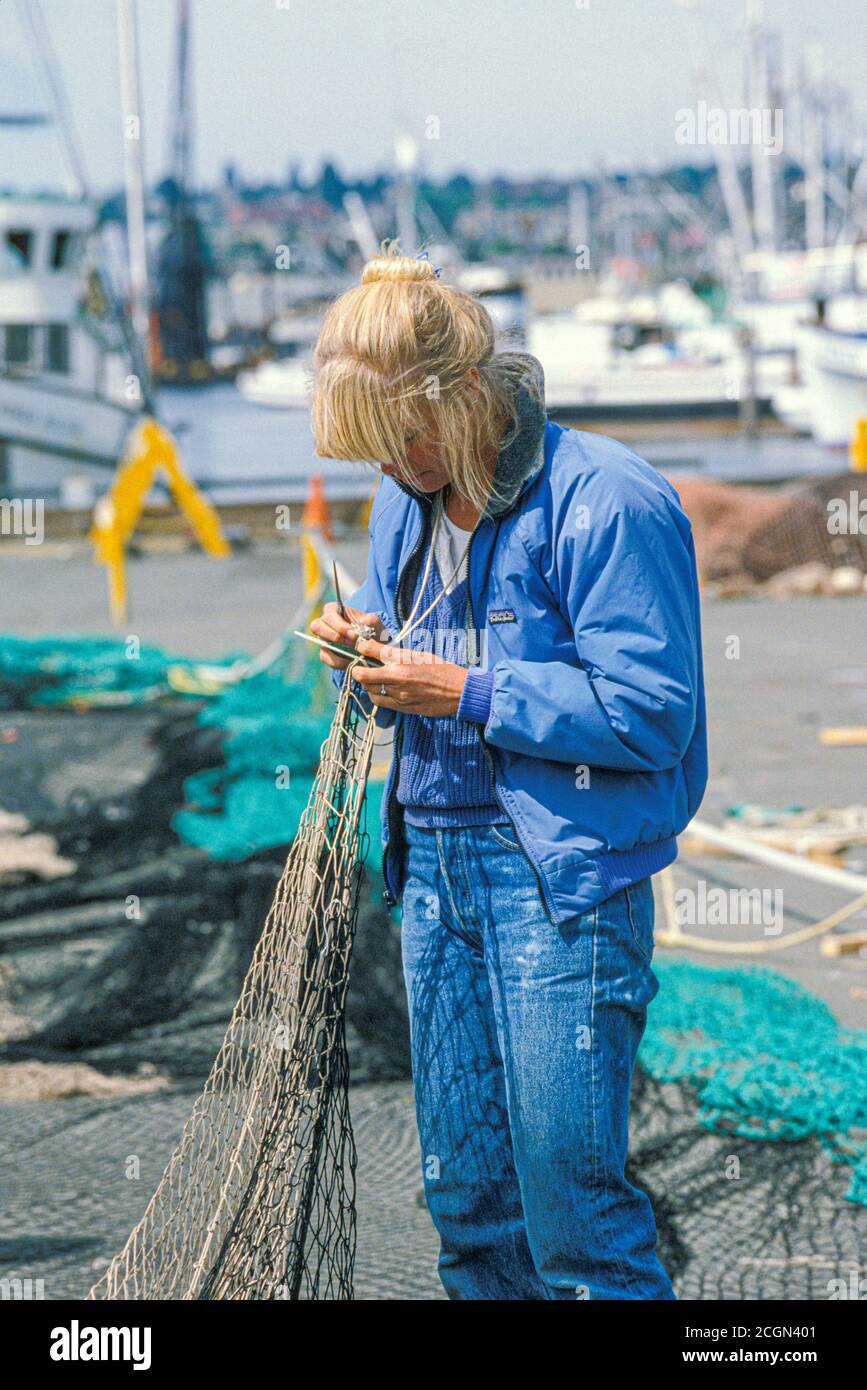 Frau, die kommerzielle Fischernetze im Fisherman’s Terminal, Seattle, Washington USA ausbessern Stockfoto