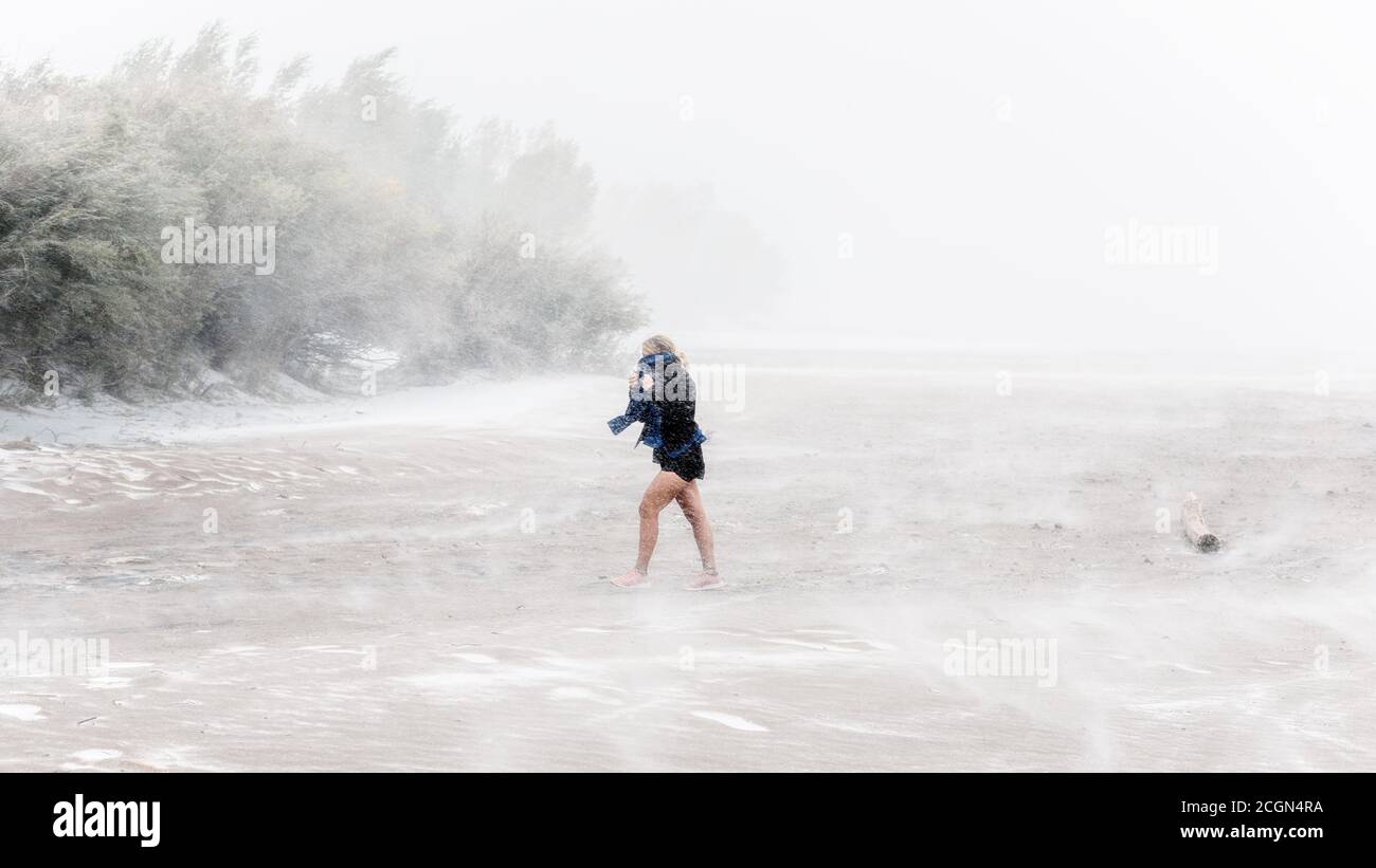 Frau, die im Great Sand Dunes National Park, Colorado, durch ein Whiteout mit Schnee, starkem Wind und Schneesturm geht Stockfoto