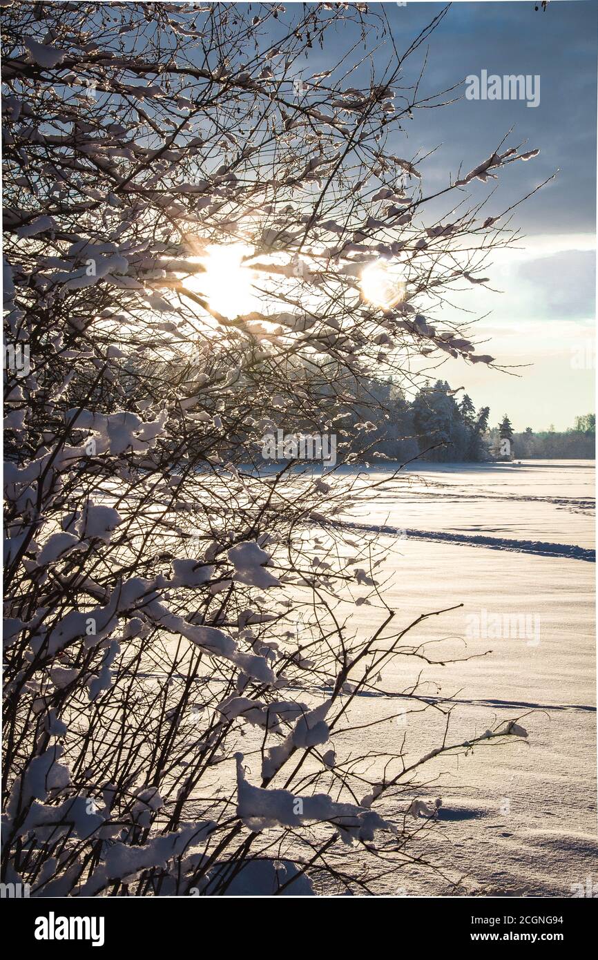 Sonniger Sonnenuntergang über einem schneebedeckten See.blauer Himmel mit Wolken.Skipisten Und Trails im Schnee Stockfoto