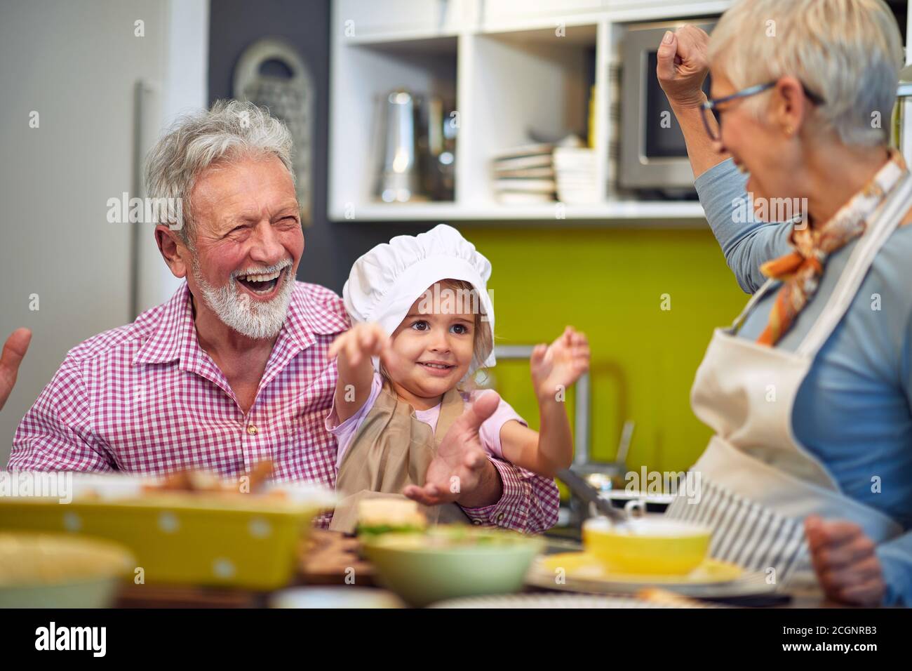 kaukasische Großeltern haben Spaß mit ihrer Enkelin in der Küche Stockfoto