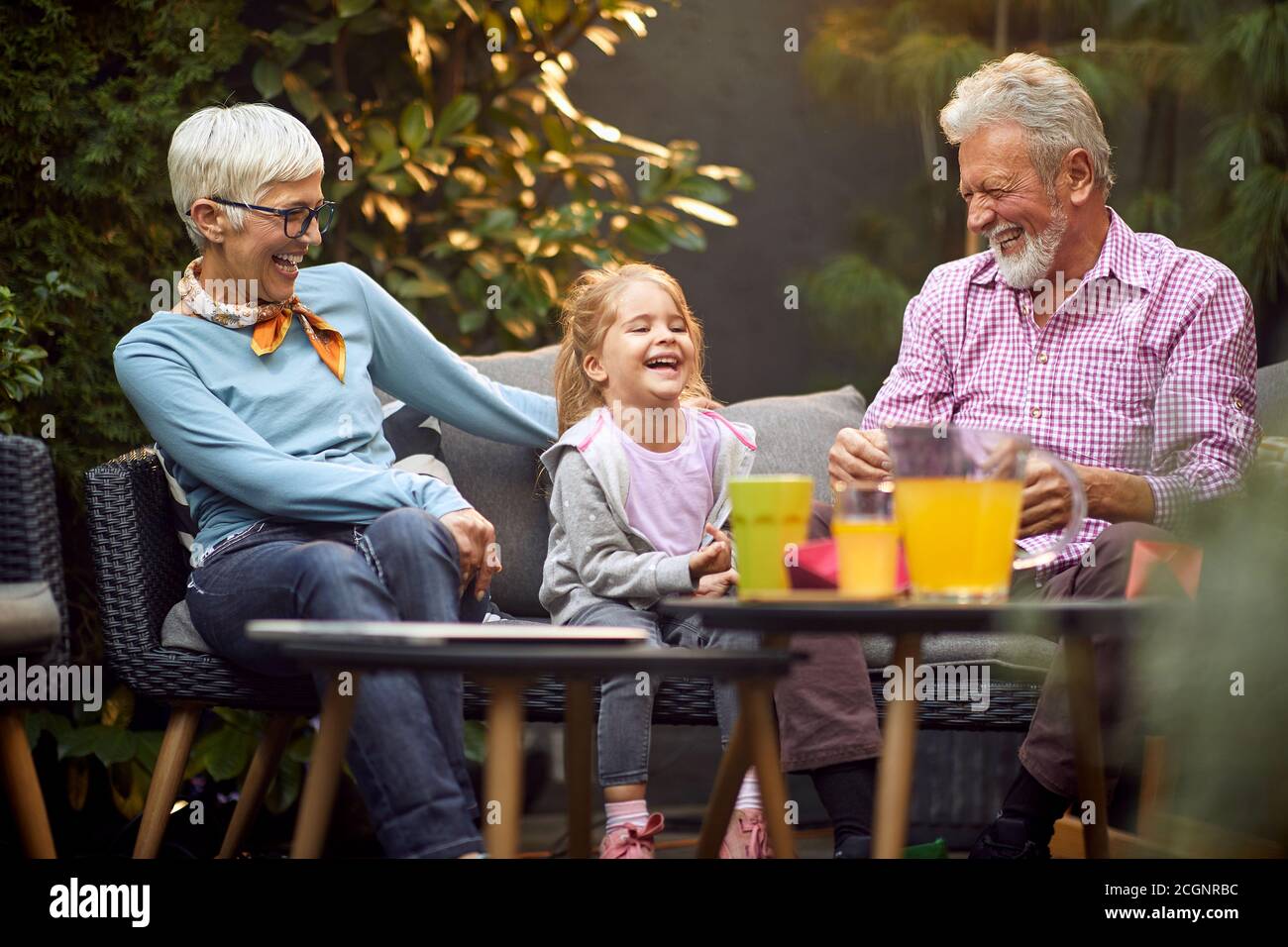 kaukasische Großeltern lachen laut mit ihrer Enkelin und haben wunderbare Zeit Stockfoto