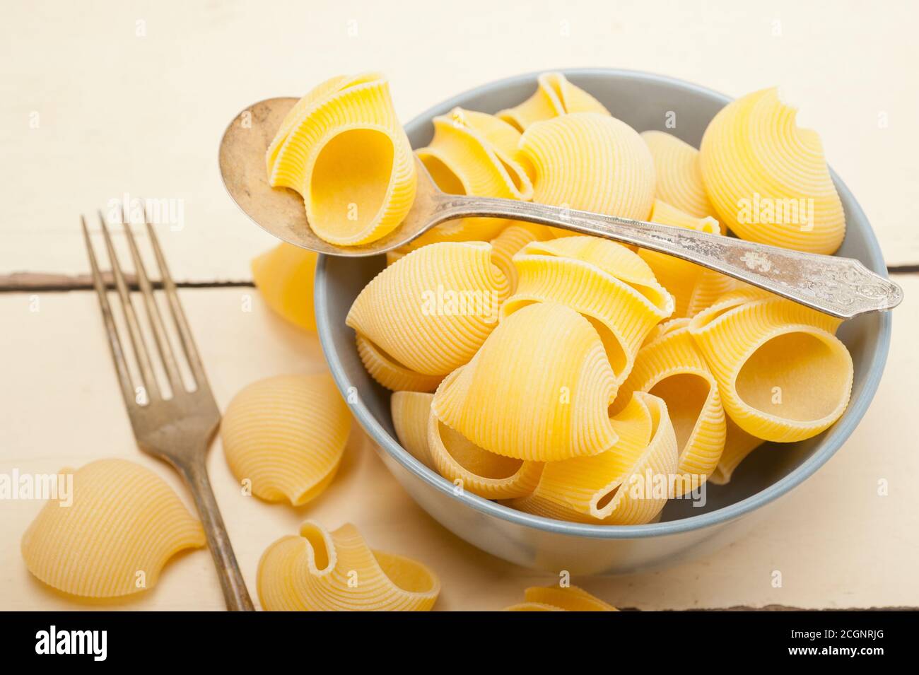 rohe italienische Schnecke Lumaconi Nudeln auf einer blauen Schüssel über rustikalen Tisch Makro Stockfoto